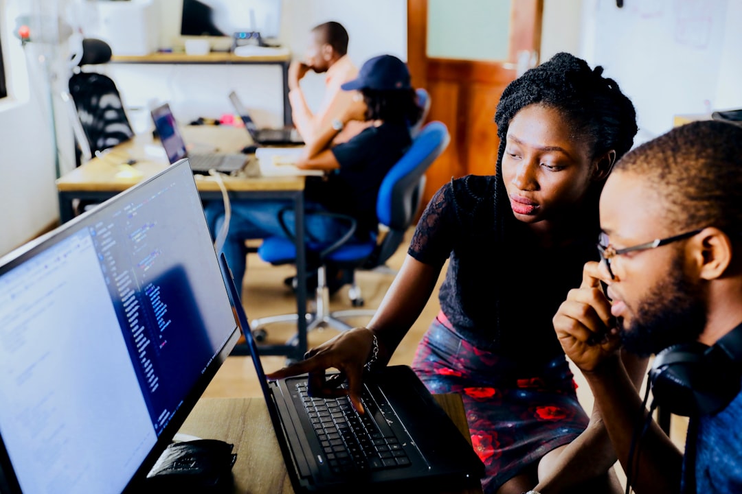 two tech workers assess code on a large desktop monitor