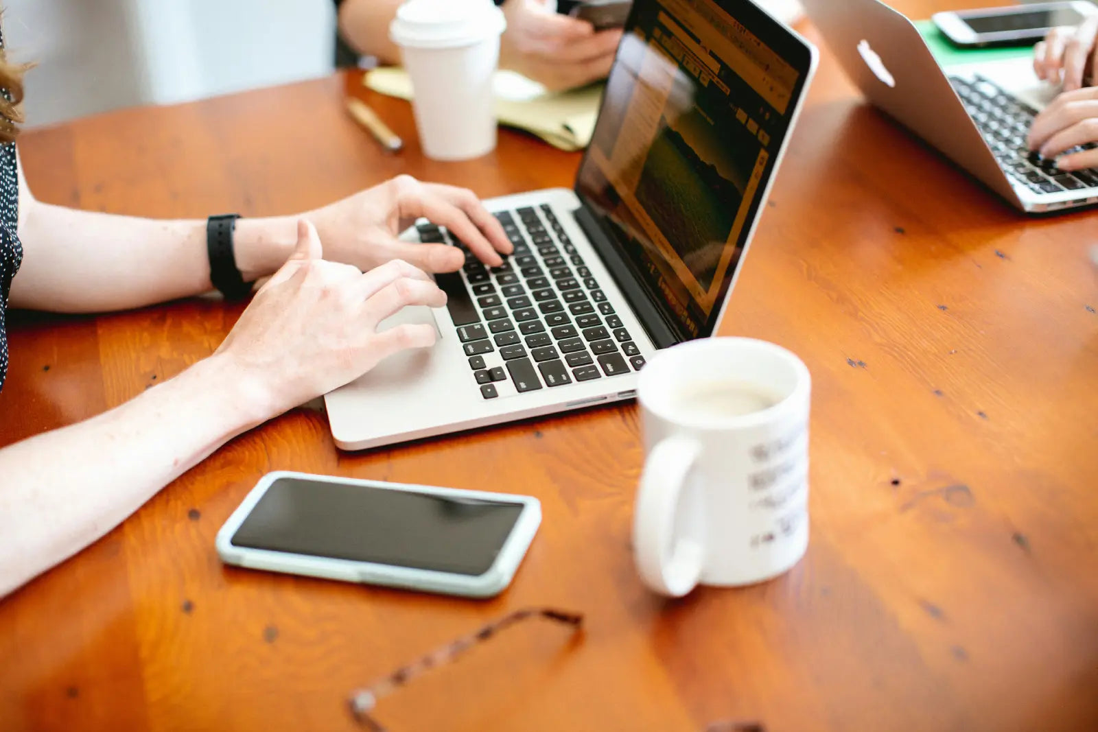 tech workers edit a website from their laptops on a large wooden table